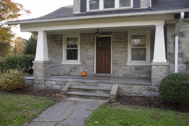 A stone craftsman porch with one engraved pumpkin on the step